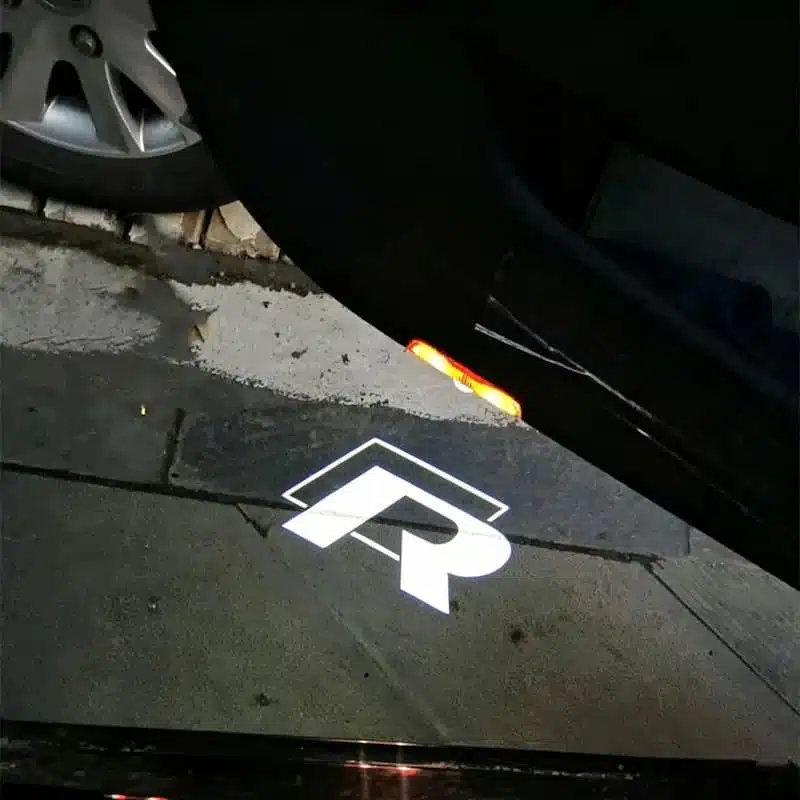 2Pcs/Set Volkswagen R Door Lights 1 Nighttime view of a Volkswagen R model with illuminated custom courtesy ghost lights shining the R sport badge onto the pavement.